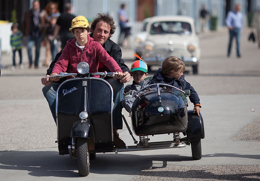 MADRID, SPAIN - JUNE 09: A man drives a Vespa motorcycle sidecar with three children at the Jarama Circuit on June 9, 2013 in Madrid, Spain. The Jarama Vintage Festival seeks to revive the 1960s, 70s and 80s attracting classic cars and motorbikes against a background of public orientated activities and shows. (Photo by Pablo Blazquez Dominguez/Getty Images)