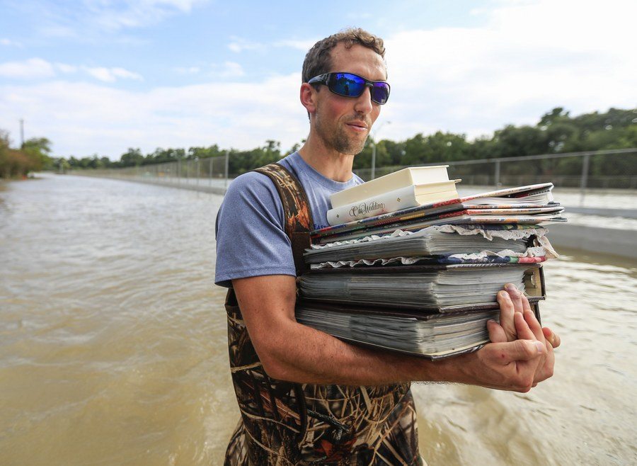 epa06172877 A man carries family photo albums from a flooded neighborhood in the aftermath of Hurricane Harvey in Houston, Texas, USA, 30 August 2017. Hurricane Harvey made landfall on the south coast of Texas as a major hurricane category 4. The last time a major hurricane of this size hit the United States was in 2005. EPA/TANNEN MAURY