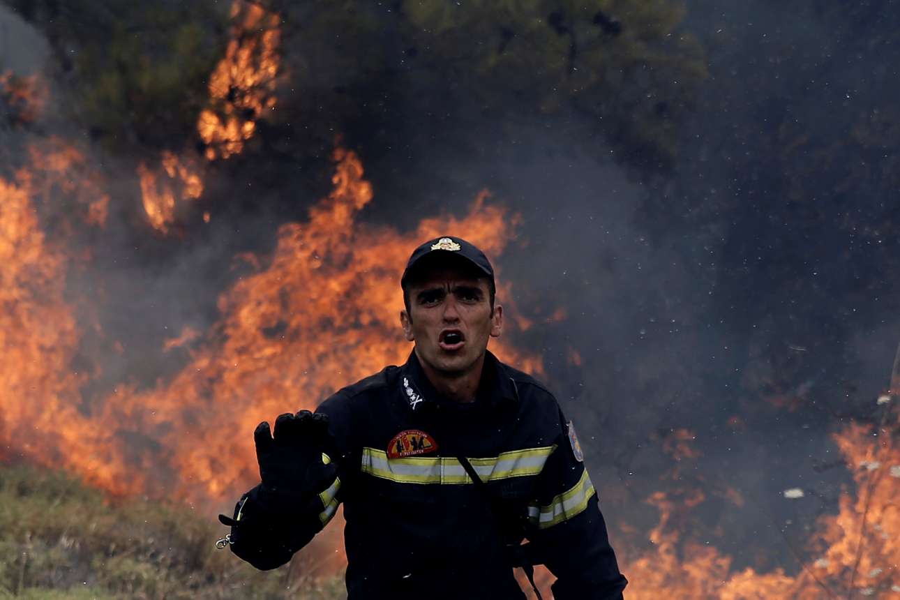 Ανήμερα Δεκαπενταύγουστος, με φόντο τις φλόγες ο πυροσβέστης προσπαθεί να απομακρύνει τον κόσμο