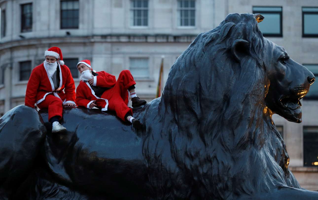 Συμμετέχοντες του Santacon, μία εκδήλωση όπου γίνεται ένα Σάββατο του Δεκεμβρίου στο Λονδίνο, κάθονται πάνω σε ένα από τα λιοντάρια της πλατείας Τραφάλγκαρ