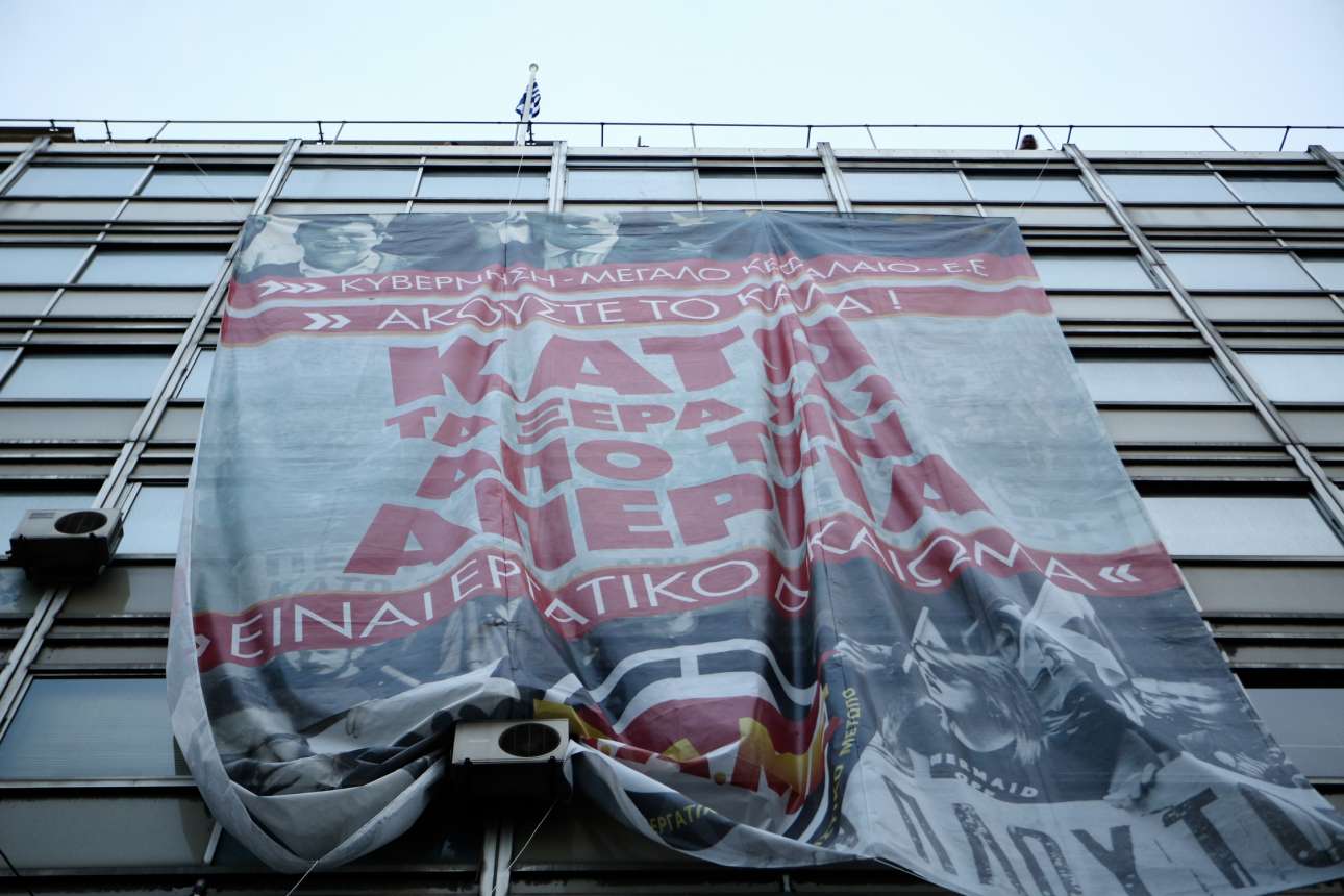 Το πανό που κρέμασαν από την ταράτσα στην πρόσοψη του κτιρίου τα μέλη του ΠΑΜΕ SOOC)