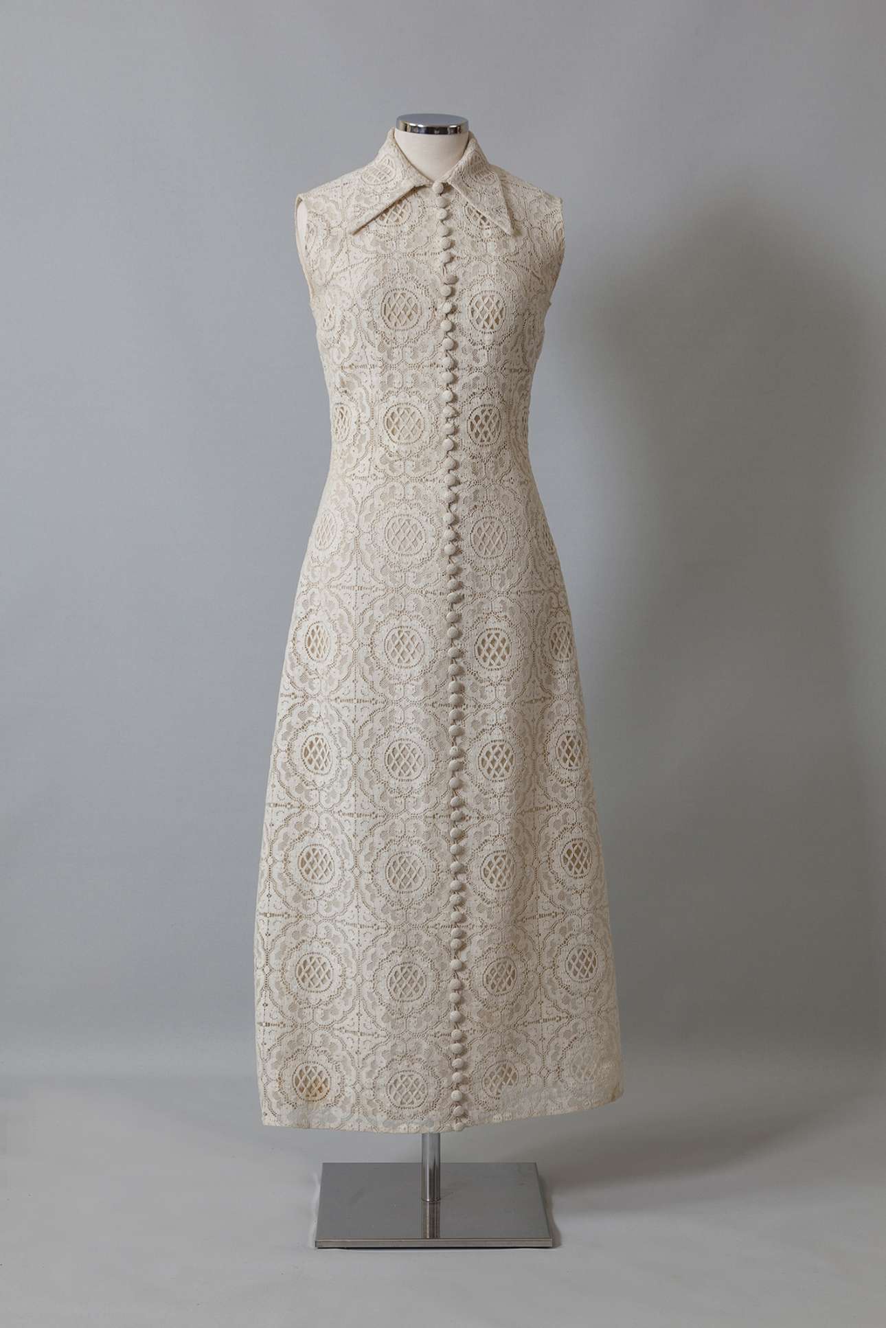 Νυφικό φόρεμα σε γραμμή Α από εκρού δαντέλα με άνθινα σχέδια. Ραμμένο από τη Μαρία Ηλιάδη, Αθήνα. Η δαντέλα αγοράστηκε στο Λονδίνο και ήταν δώρο της Ιωάννας Παπαντωνίου. Φορέθηκε από τη Βάσω Κατσιβαρδάκου στον γάμο της με τον Γιάννη Ζέρβα στον Ι.Ν. Αγίου Νικολάου Γλυφάδας στις 6 Αυγούστου 1970. Δωρεά: Βάσω Ζέρβα (Συλλογή ΠΛΙ)