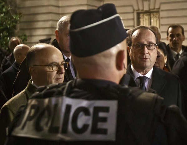 French President Francois Hollande (R) and French Interior Minister Bernard Cazeneuve (L) talk to a police officer as they visit security forces near the Champs Elysees Avenue in Paris, France, December 31, 2015.  REUTERS/Michel Euler/Pool
