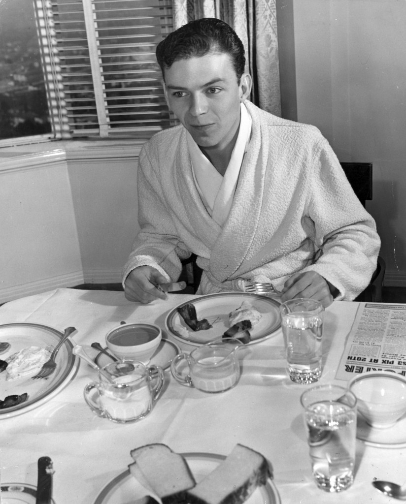 Γύρω στο 1940, ο νεαρός Φρανκ Σινάτρα,με τη ρόμπα του, απολαμβάνει για πρωινό αυγά με μπέικον (Hulton Archive/Getty Images/Ιdeal Image)