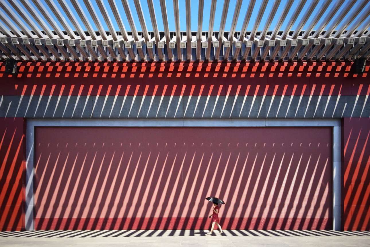 Βραβείο κατηγορίας Κινητό Τηλέφωνο: «Το κόκκινο της Κίνας». Μια γυναίκα με κόκκινο φόρεμα περπατάει μπροστά από έναν κόκκινο τοίχο στην Κίνα