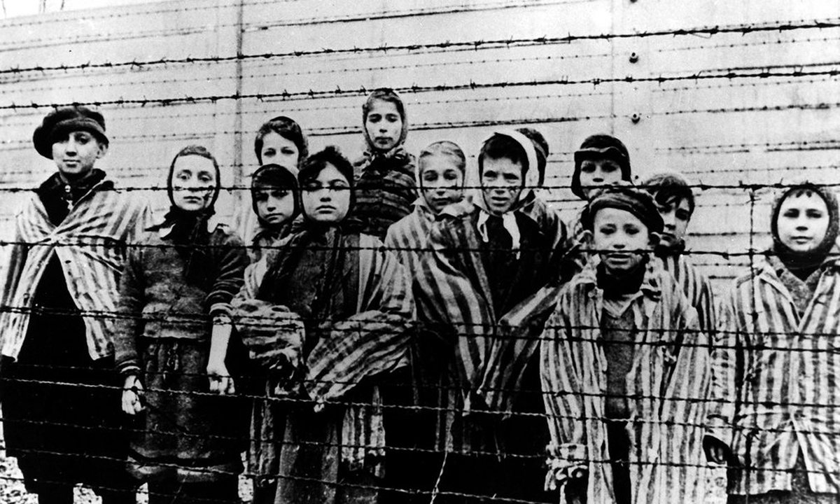 Παιδιά κοιτούν πίσω από το συρματόπλεγμα στο στρατόπεδο συγκέντρωσης του Αουσβιτς