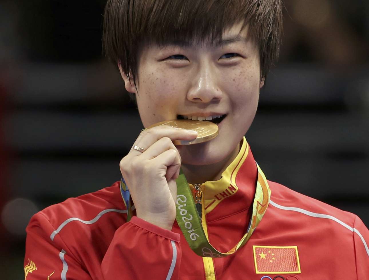 Η επίσης Κινέζα Ντιγκ Νιγκ δαγκώνει το χρυσό της μετάλλιο έχοντας νικήσει την κινέζα αντίπαλο της, Λι Ξιαόξια, στο πινγκ πονγκ