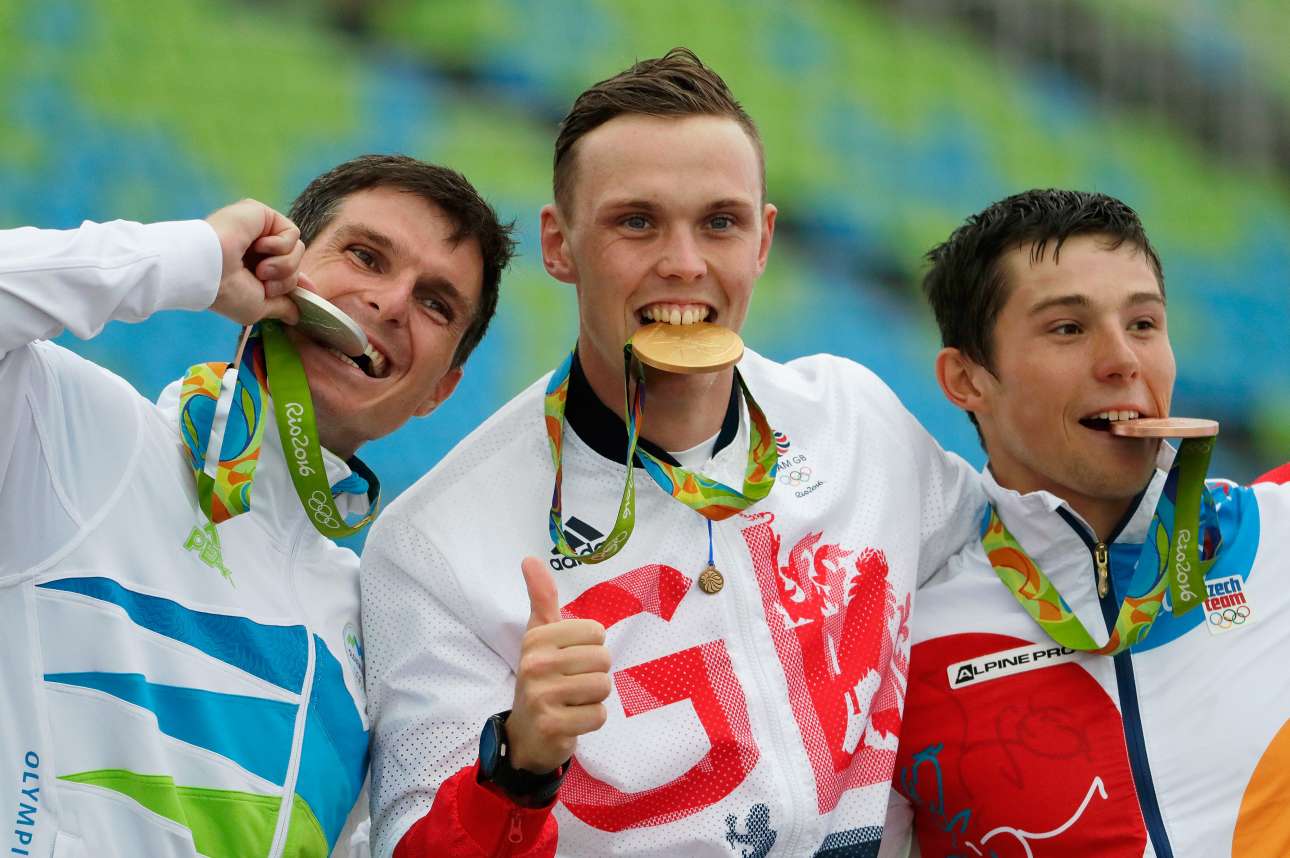 Ο Σλοβένος Πίτερ Κάουζερ με το ασημένιο, ο Βρετανός Τζόσεφ Κλαρκ με το χρυσό και ο Τσέχος Τζίρι Πρσκάβιτς με το χάλκινο μετάλλιο στο στόμα, γιορτάζουν στο βάθρο μετά τον τελικό ανδρών στο καγιάκ