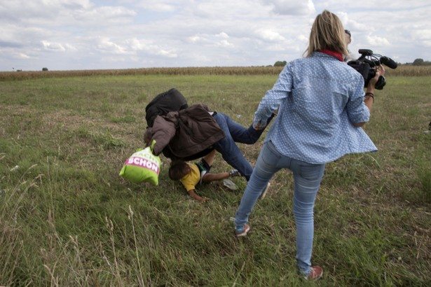 FILE PHOTO: A migrant carrying a child falls after tripping on TV camerawoman (R) Petra Laszlo while trying to escape from a collection point in Roszke village, Hungary, September 8, 2015. REUTERS/Marko Djurica/File photo - RTX2JQXV