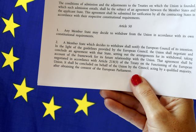 FILE PHOTO - Article 50 of the EU's Lisbon Treaty that deals with the mechanism for departure is pictured near an EU flag following Britain's referendum results to leave the European Union, in this photo illustration taken in Brussels, Belgium, June 24, 2016. REUTERS/Francois Lenoir/Illustration/File Photo