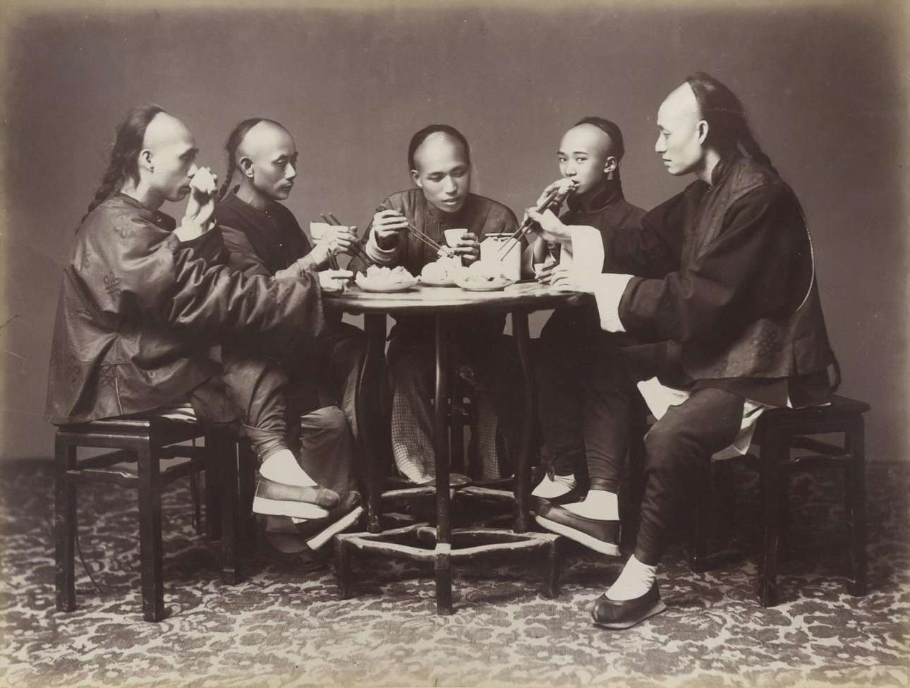 Ανδρες δειπνούν μαζί στο Χονγκ Κονγκ το 1880. Υπό την δυναστεία των Τσινγκ, κάθε Κινέζος Χαν έπρεπε να έχει τα μαλλιά του σε μακριές πλεξούδες
