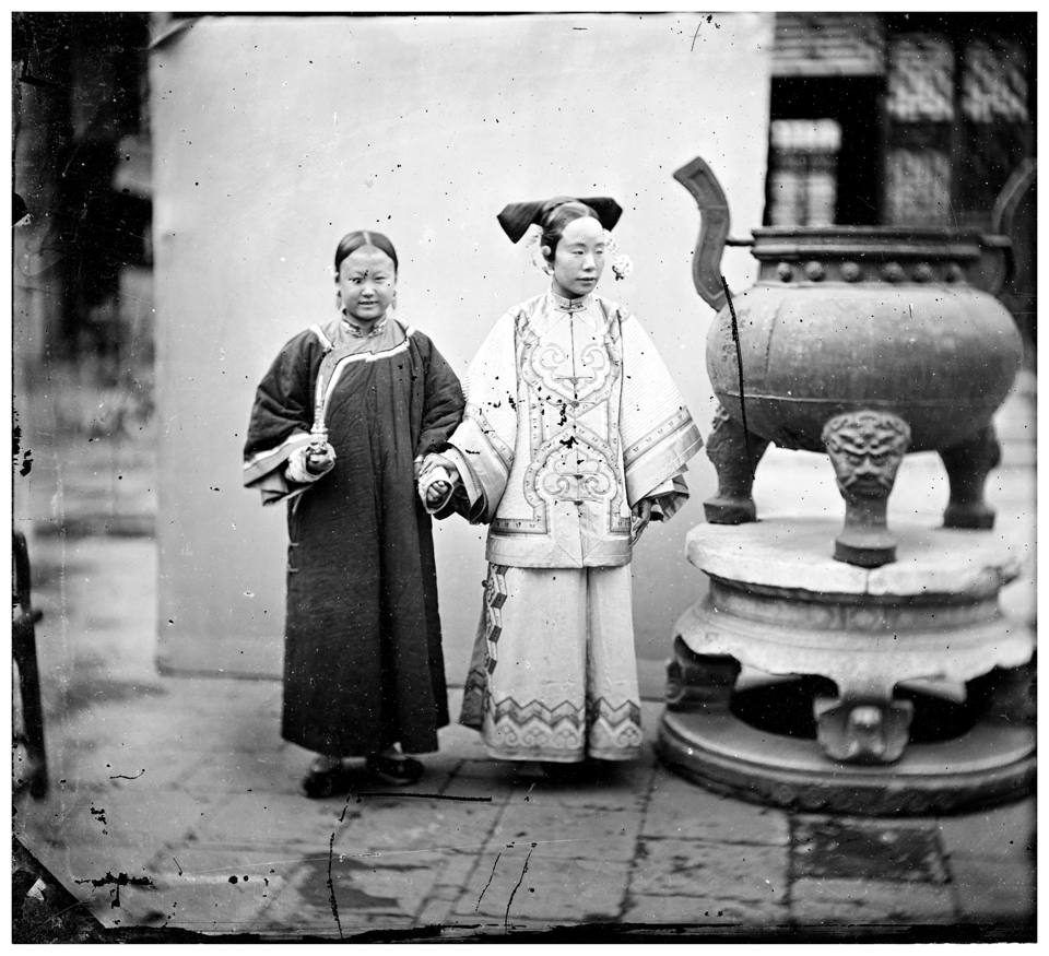 Μία γυναίκα ποζάρει με την υπηρέτρια της δίπλα σε ένα μπρούτζινο θυμιατό, στο Πεκίνο το 1869