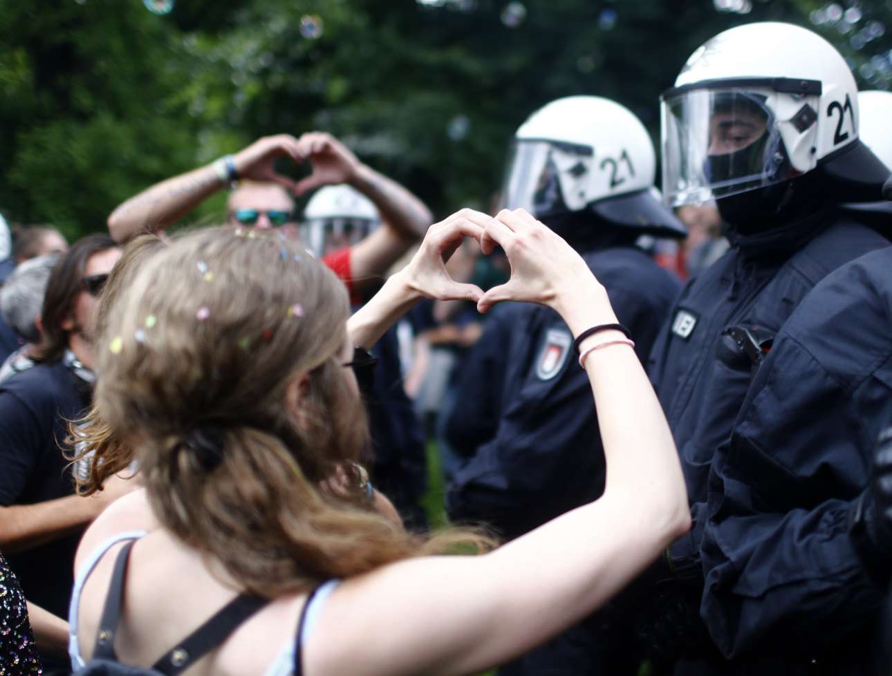 «Κάντε έρωτα, όχι πόλεμο» ή τέλως πάντων κάτι τέτοιο εν έτει 2017. Η διαδηλώτρια σχηματίζει το σήμα της καρδιάς μπροστά στον ατάραχο αστυνομικό