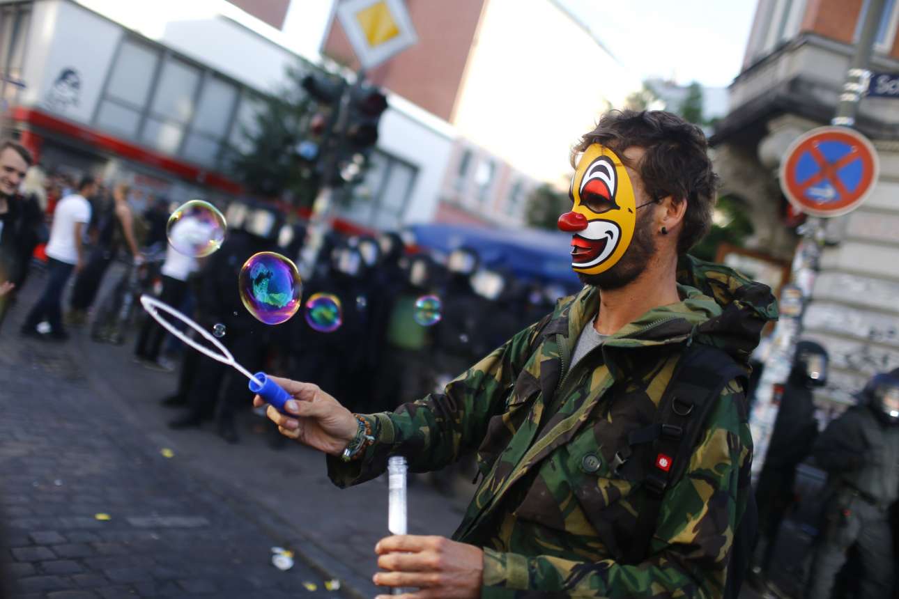 Φαντασία στη διαμαρτυρία. Φορώντας μια μάσκα αρλεκίνου ο διαδηλωτής παίζει με φούσκες στη μεγάλη πορεία κατά του G20 το μεσημέρι του Σαββάτου