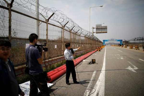 A journalist makes a news report at a checkpoint on the Grand Unification Bridge that leads to the Peace House, the venue for the Inter-Korean summit, near the demilitarized zone separating the two Koreas, in Paju, South Korea, April 26, 2018. REUTERS/Kim Hong-Ji