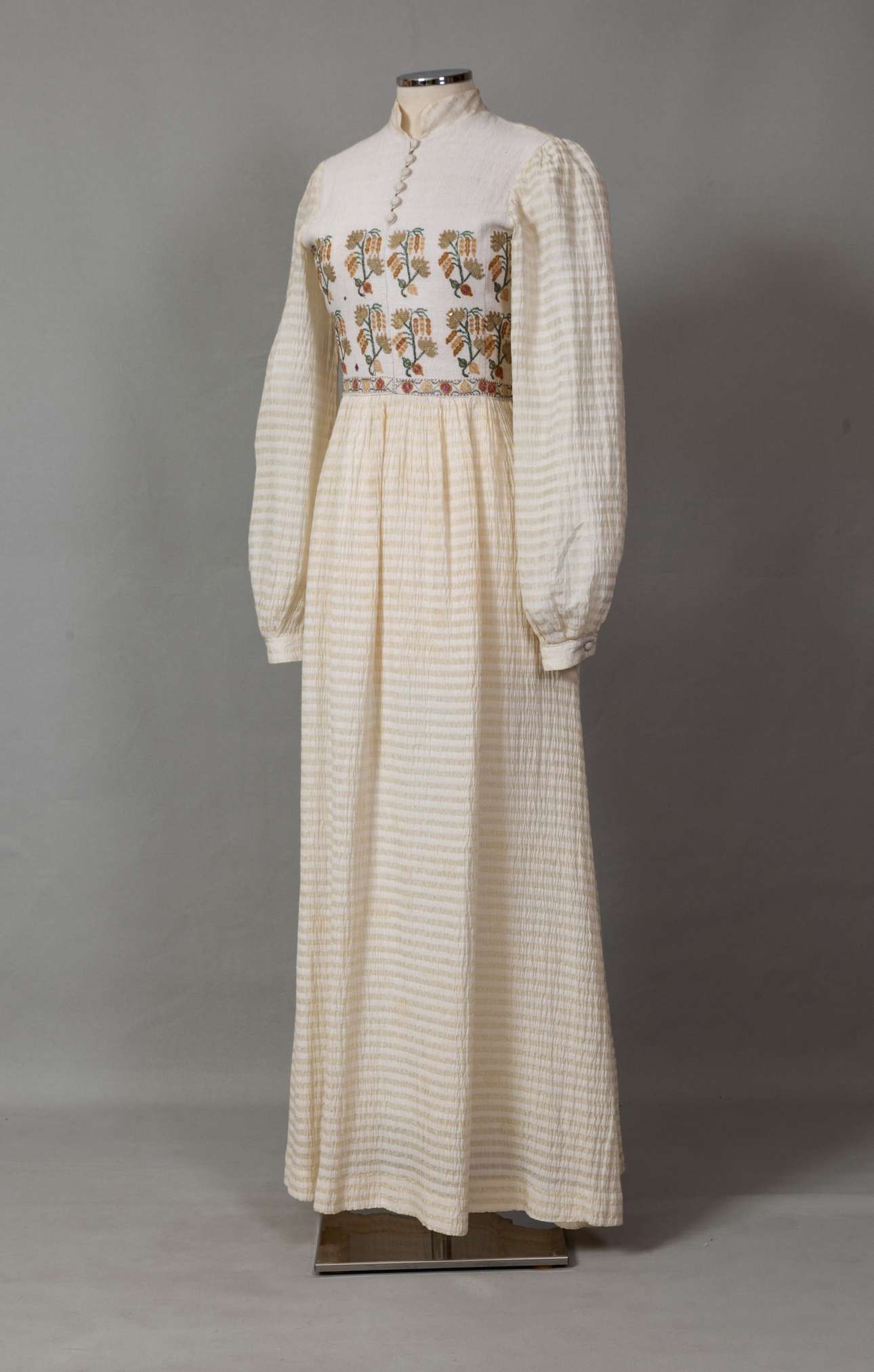 Νυφικό φόρεμα από υπόλευκο μετάξι, υφασμένο στον αργαλειό από την Όλγα Κεχάεφ, Αθήνα. Διακόσμηση με κεντημένο τσεβρέ στο στήθος. Φορέθηκε από τη Δέσποινα Σπαθαράκη στον γάμο της με τον Νικόλαο Τσιγκρή στον Άγιο Γεώργιο Αθηνών στις 4 Ιανουαρίου 1981. Δωρεά: Δέσποινα Τσιγκρή (Συλλογή ΠΛΙ)