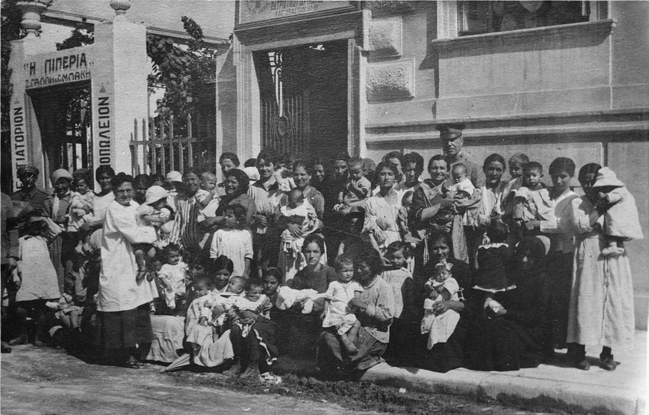 «Κάποιοι μελλοντικοί Αθηναίοι». Μητέρες με τα παιδιά τους αγκαλιά έξω από κλινική του Αμερικανικού Ερυθρού Σταυρού στην Αθήνα. Εκεί πήγαιναν τα παιδιά τους για να ζυγιστούν, να καθαριστούν και να πάρουν φάρμακα, ενώ οι ίδιες μάθαιναν πώς να τα φροντίζουν σωστά. Κάθε ημέρα 250 παιδιά επισκέπτονταν την κλινική