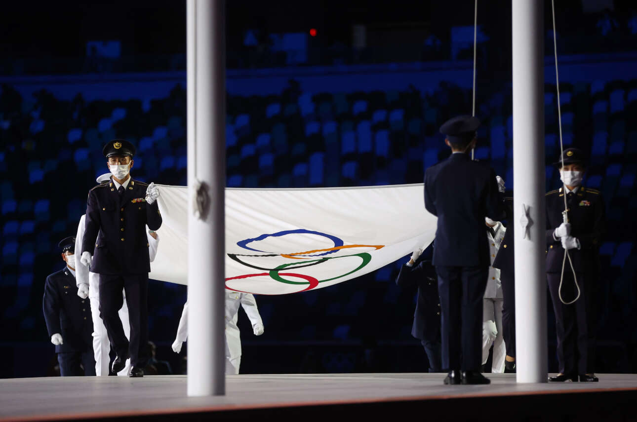 Η σημαία των Ολυμπιακών Αγώνων μεταφέρεται από τους έξι σημαιοφόρους για να τοποθετηθεί στον ιστό