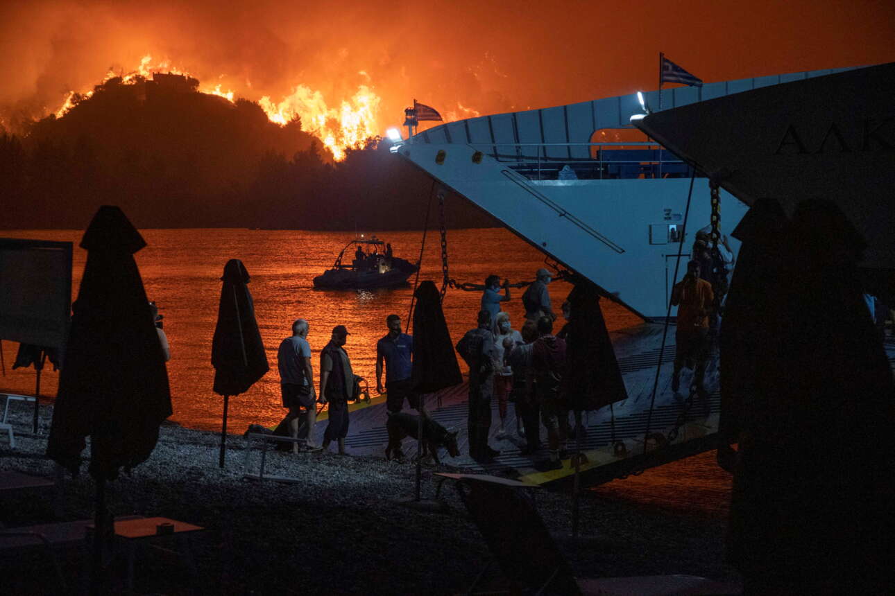 Οι φλόγες κατακαίνε ό,τι βρουν μπροστά τους, οι τελευταίοι κάτοικοι και εκδρομείς επιβιβάζονται στο πλοίο