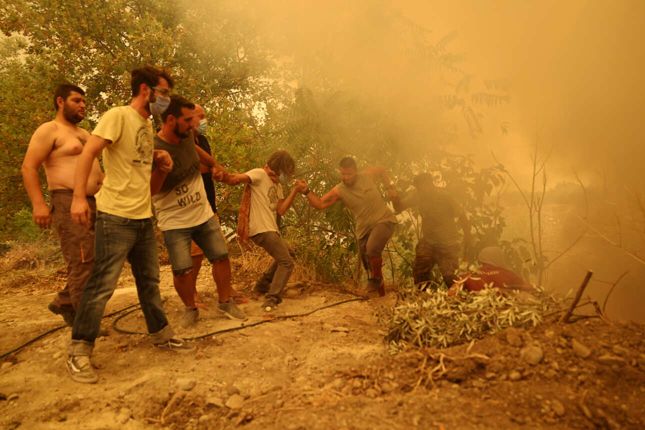Στις Γούβες κάτοικοι σχηματίζουν αλυσίδα για να βοηθήσουν έναν συμπολίτη τους που με μια μάνικα σβήνει τη φωτιά στο χαντάκι