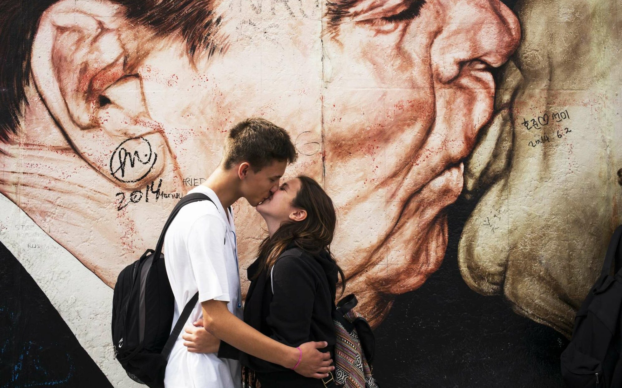 Ιούλιος 2014, Βερολίνο: Ενα ζευγάρι φιλιέται μπροστά από το πιο διάσημο έργο του ρώσου ζωγράφου Ντμίτρι Βρούμπελ, γνωστό ως «Θεέ μου, βοήθησέ με να επιβιώσω από αυτή τη θανατηφόρα αγάπη» σε ένα τμήμα του πρώην Τείχους του Βερολίνου στην East Side Gallery