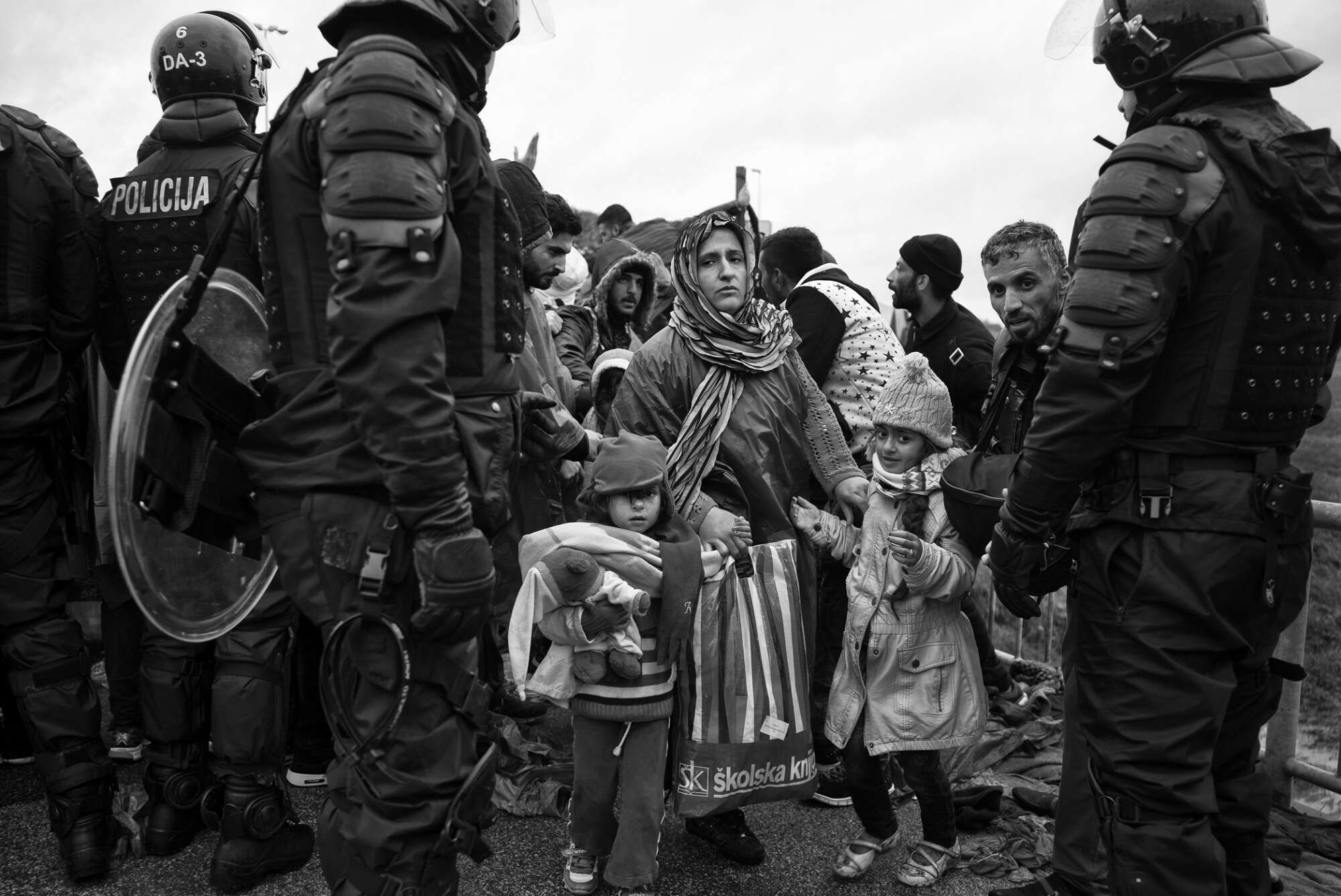 Οκτώβριος 2015, Κροατία: Στο συνοριακό πέρασμα του Τίμοβετς, μια μητέρα οδηγεί τα παιδιά της μέσα από τη γραμμή της σλοβενικής αστυνομίας. Οι καθυστερήσεις που προκαλούνται από τους περιορισμούς της ΕΕ δημιουργούν ένταση και θυμό καθώς οι άνθρωποι προσπαθούν να συνεχίσουν το ταξίδι τους προς τη Δυτική Ευρώπη