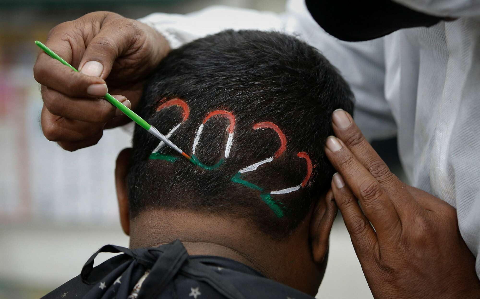 Μπαρμπέρης στο Αχμενταμπάντ της Ινδίας βάφει το 2022 στα χρώματα της ινδικής σημαίας, στο κεφάλι του πελάτη του