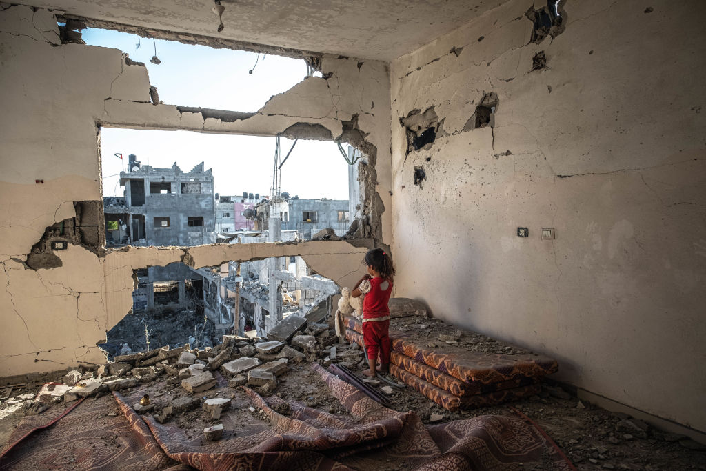 Ενα κορίτσι κοιτάζει από τον κατεστραμμένο τοίχο του σπιτιού της στη Γάζα. Οι κάτοικοι της παλαιστινιακής πόλης έπρεπε να δουλέψουν σκληρά για να ξανακάνουν τα σπίτια τους κατοικήσημα