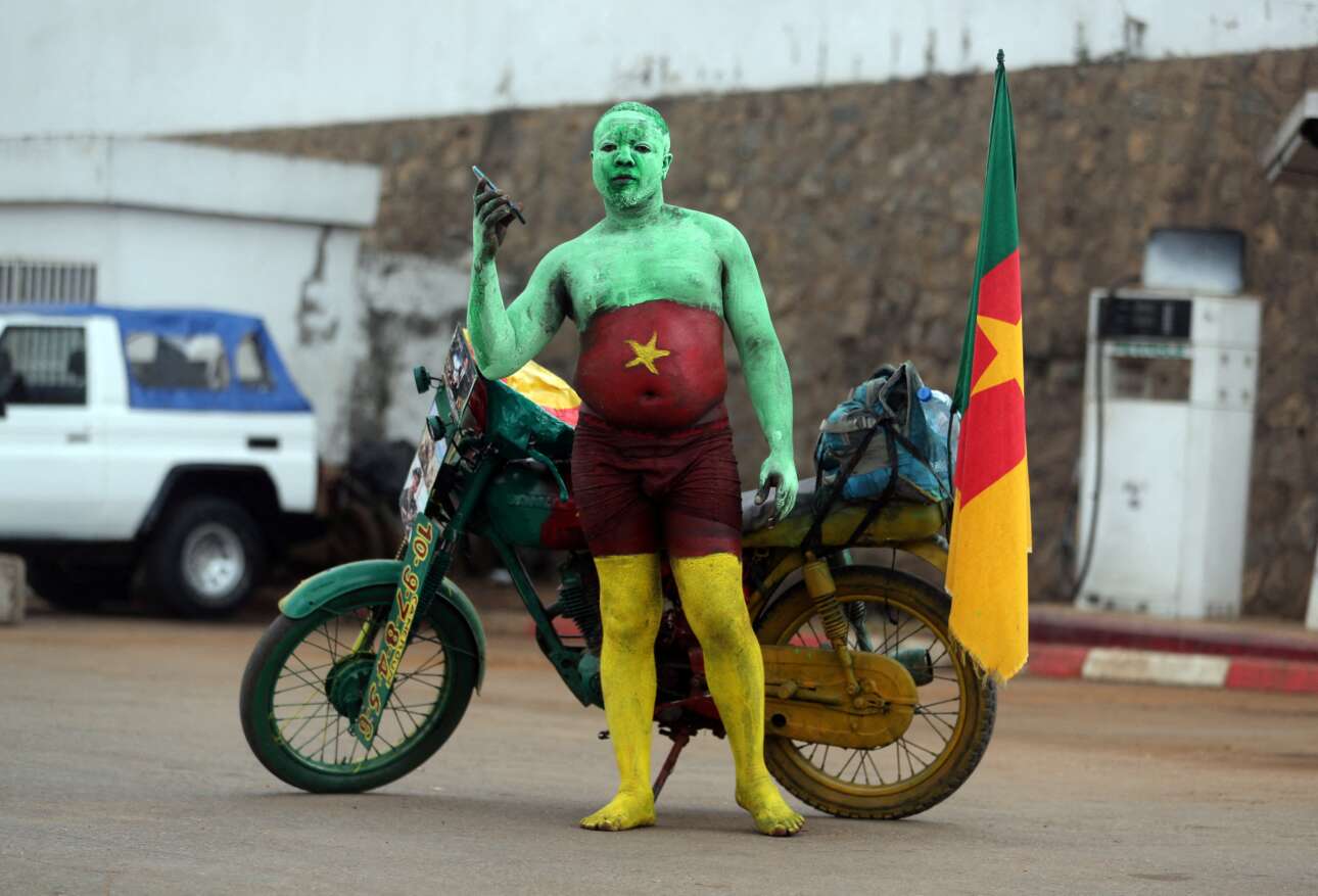 Και από τα σαλόνια στα αλώνια, με αυτό το γραφικό πορτρέτο φιλάθλου που τραβήχτηκε έξω από το γήπεδο της Γιαουντέ, πρωτεύουσας του Καμερούν: βλέπουμε δίπλα στο φοβερό μηχανάκι του έναν ντούρο οπαδό της Εθνικής Καμερούν, βαμμένο πατόκορφα στα εθνικά  χρώματα, λίγο προτού αρχίσει το ματς με την Μπουρκίνα Φάσο για το Αφρικανικό Κύπελλο 