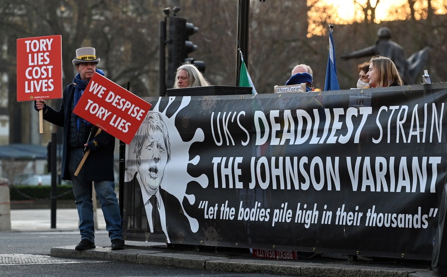 «Το πλέον θανατηφόρο στέλεχος του κορονοϊού είναι η παραλλαγή Τζόνσον» γράφει το πανό των διαδηλωτών που συγκεντρώθηκαν έξω από τη βρετανική Βουλή – το hangover από εκείνο το πάρτι στον κήπο της Downing Street 10, τον Μάιο του 2020, όταν το γενικό λοκντάουν νέκρωσε το Λονδίνο, είναι βαρύ, χειρότερο από ίωση, δεν τον πιάνουν παυσίπονα, δεν το απαλύνει ο χρόνος