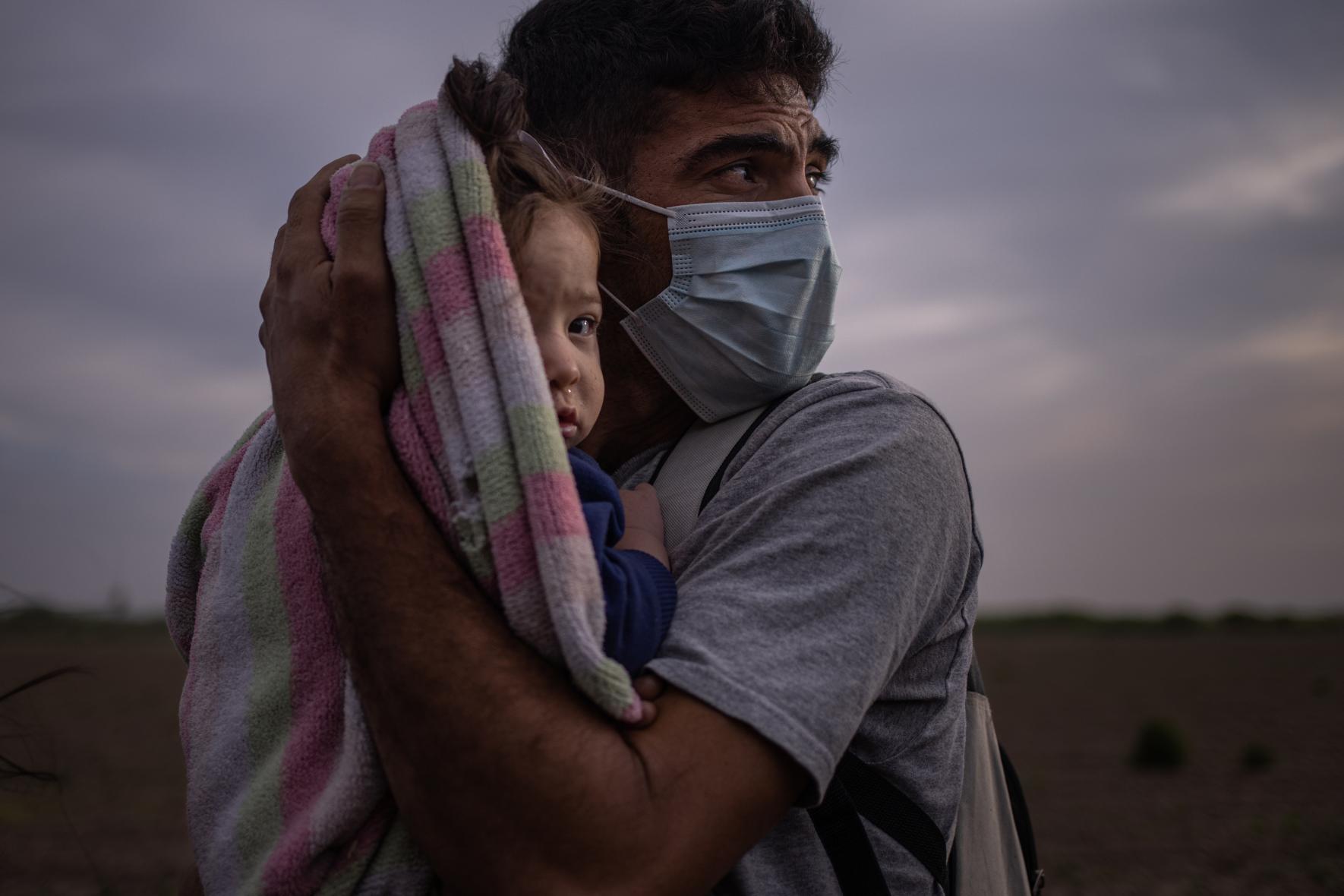 Ο Φρανσίσκο Αντόνιο Ναβάρο, 34 ετών, από την Ονδούρα, μετανάστης που ζητά άσυλο, κρατά στην αγκαλιά του την κόρη του Μέγκαν στην αμερικανική όχθη του ποταμού Ρίο Γκράντε καθώς περιμένουν τη μεταφορά τους σε κέντρο ταυτοποίησης 