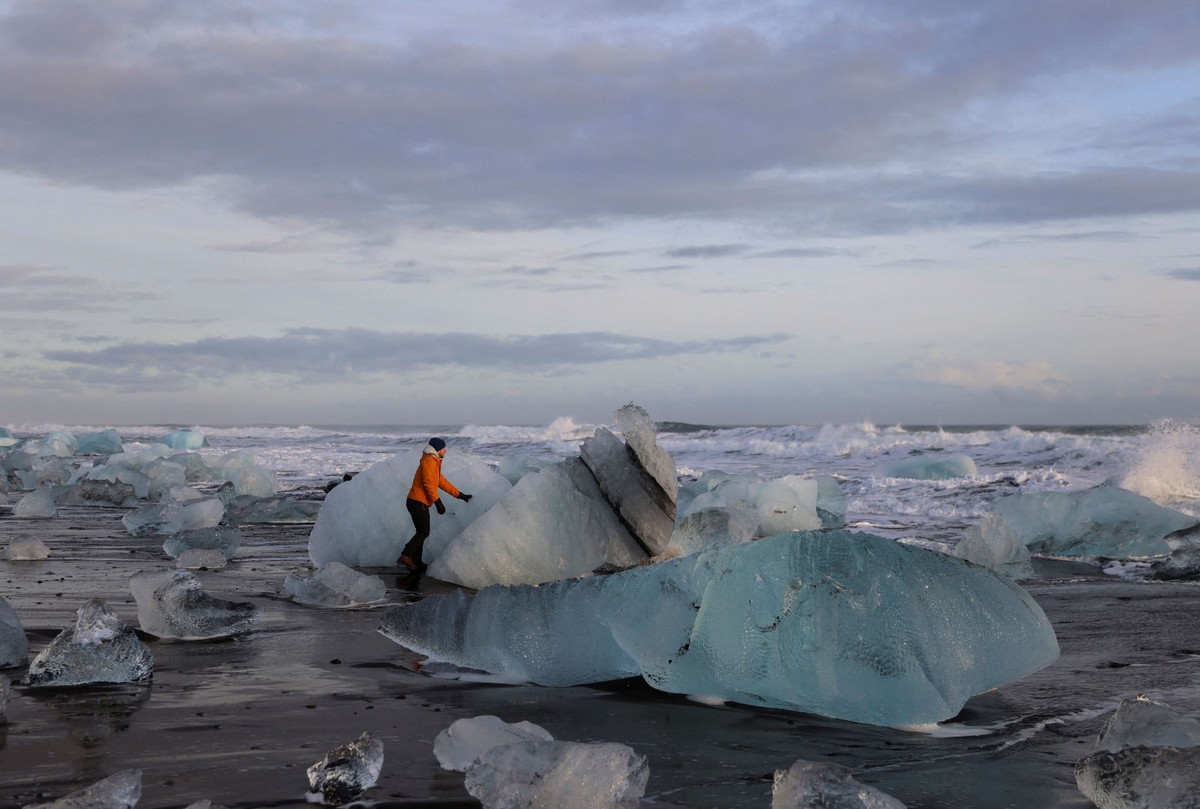 Ενας τουρίστας παρατηρεί  μεγάλα κομμάτια πάγου σε μια παραλία κοντά στη λιμνοθάλασσα του παγετώνα Γιουκουλσαρλόν στις 17 Φεβρουαρίου 2022