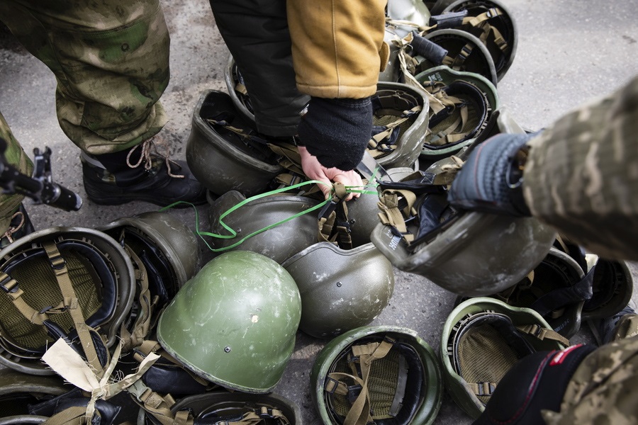 Πολίτες και μέλη διαφόρων παραστρατιωτικών ομάδων έχουν συγκροτήσει στο Κίεβο τις λεγόμενες Δυνάμεις Τοπικής Αμυνας – στο καρέ διαμοιράζονται κράνη στα μέλη τους, ώστε να πολεμήσουν και αυτοί στα μετόπισθεν