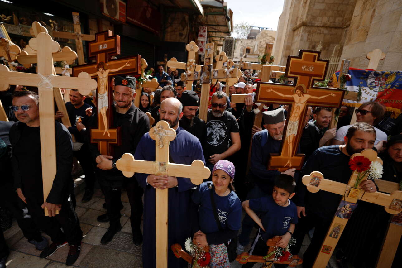 Προσκυνητές στην Ιερουσαλήμ περπατούν στην παλιά πόλη, κρατώντας στα χέρια τους ξύλινους Σταυρούς