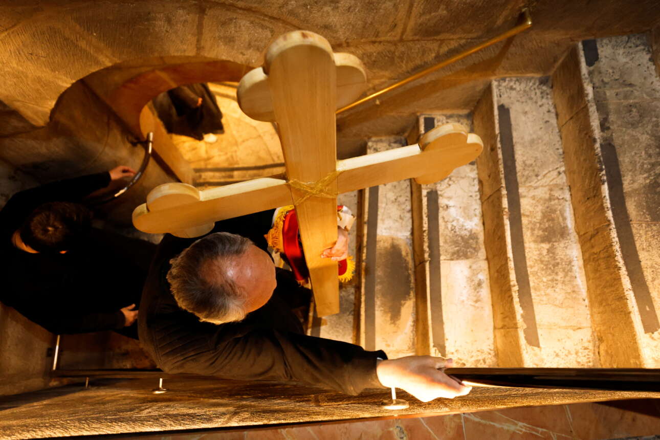 Προσκυνητής την ώρα της Θείας Λειτουργίας κουβαλάει τον Σταυρό στον ναό της Αναστάσεως στην Ιερουσαλήμ 