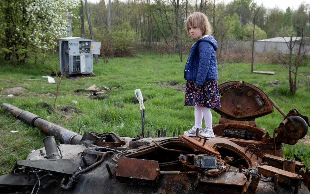 Ενα κοριτσάκι πάνω σε ένα κατεστραμμένο ρωσικό τανκ έξω από το Κίεβο κοιτάζει θλιμμένο τον φακό