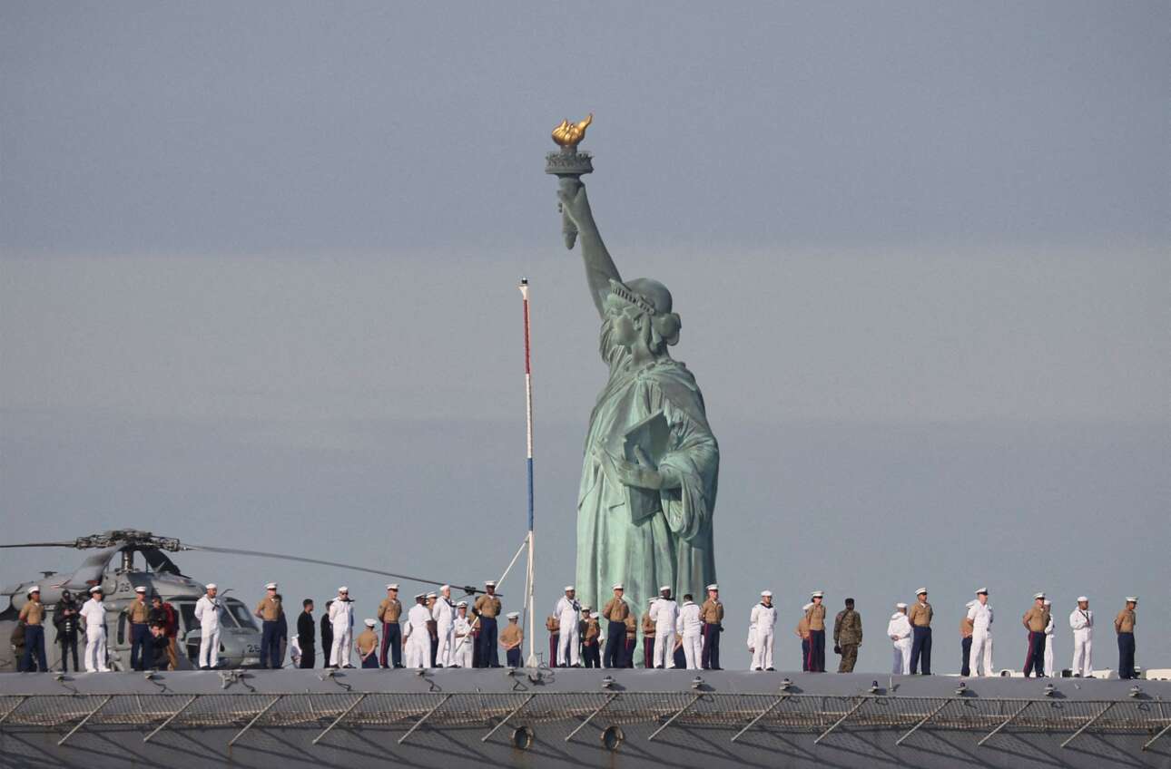 Ναύτες και πεζοναύτες παραταγμένοι στο κατάστρωμα του καταπλέοντος στη Νέα Υόρκη «USS Bataan», ενός εκ των προηγμένων πλοίων του αμερικανικού Πολεμικού Ναυτικού – το Αγαλμα της Ελευθερίας κάνει ότι κοιτάζει αλλού, ωστόσο τους βλέπει