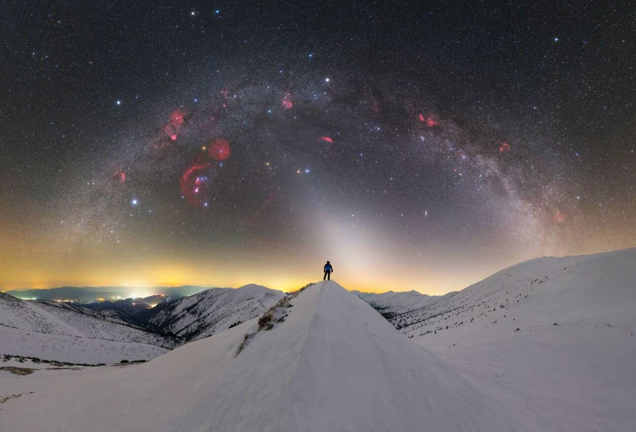 Μια ανθρώπινη φιγούρα στέκεται πάνω σε μια χιονισμένη κορυφή της οροσειράς Low Tatras στη Σλοβακία και από πάνω της εμφανίζεται ένα τεράστιο γαλαξιακό φωτοστέφανο