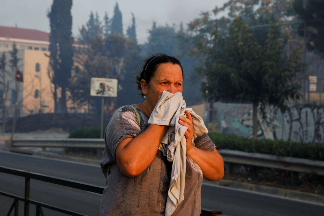 Μία γυναίκα προσπαθεί να προστατευθεί από τους καπνούς στην Παλλήνη