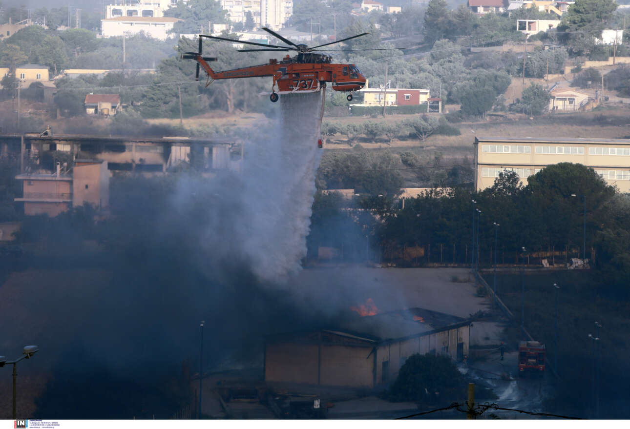 Ρίψεις νερού από ελικόπτερο σε φλεγόμενες εγκαταστάσεις και σπίτια στην Παλλήνη 
