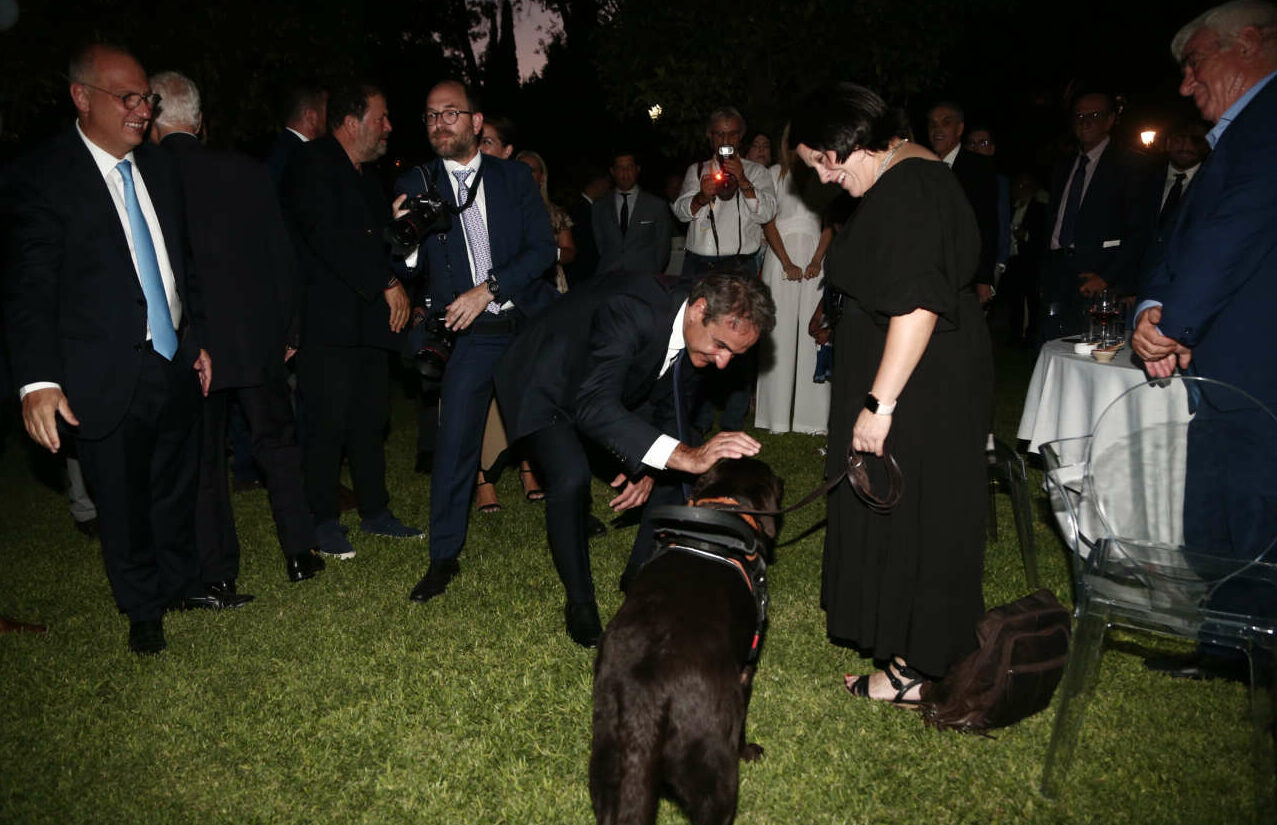 O Κυριάκος Μητσοτάκης χαιρετά τον σκύλο-συνοδό της καλεσμένης της Προέδρου 