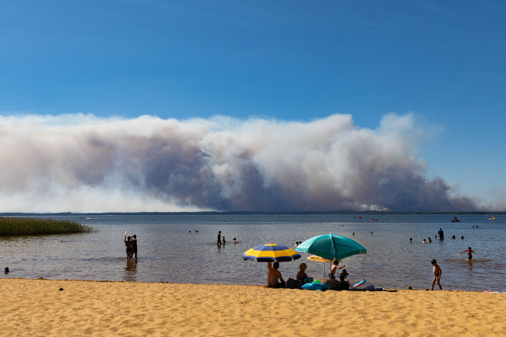 Λουόμενοι στη λίμνη Sanguinet παρακολουθούν τον καπνό που βγαίνει από το φλεγόμενο δάσος Teste-de-buch στη Γαλλία
