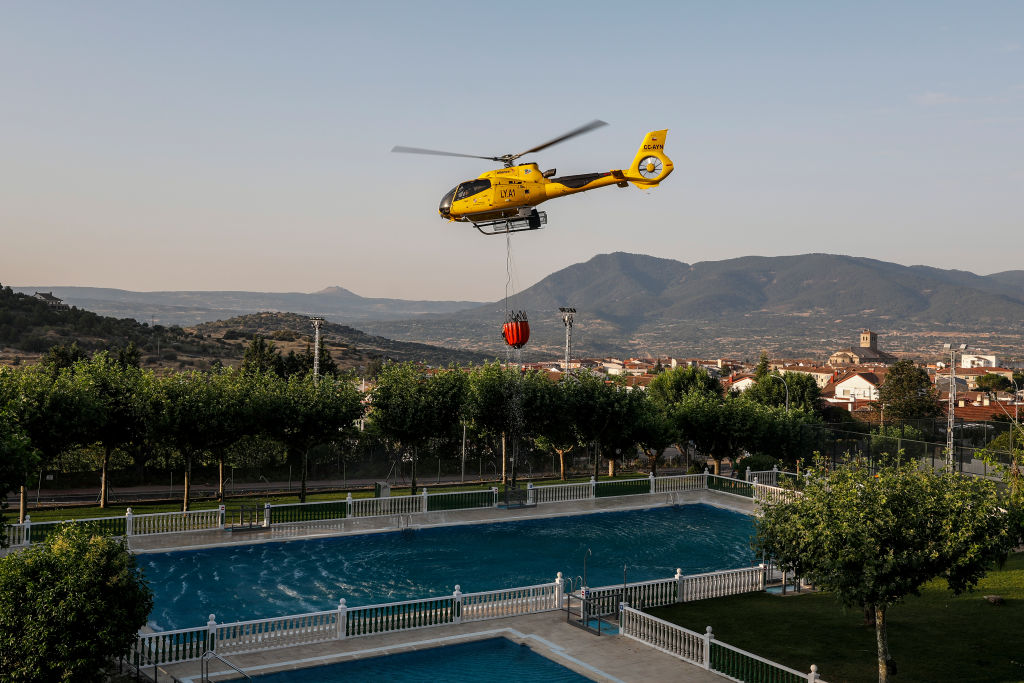 Πυροσβεστικό ελικόπτερο συλλέγει νερό από μια πισίνα για να αντιμετωπίσει τη δασική πυρκαγιά στο Σεμπρέρος, στην Aβιλα της Ισπανίας