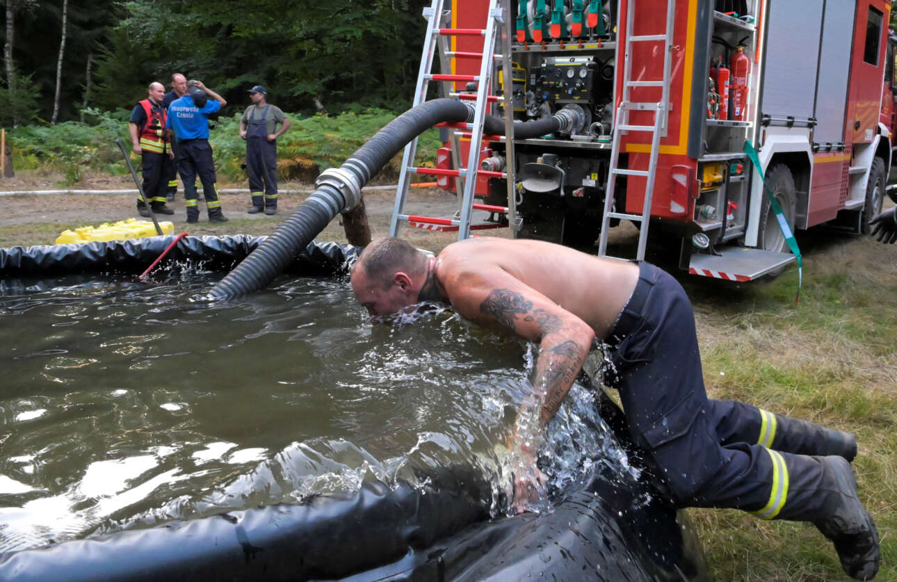 Ενας πυροσβέστης βουτάει το κεφάλι του σε δεξαμενή νερού της Πυροσβεστικής για να συνέλθει μετά την κατάσβεση δασικής πυρκαγιάς κοντά στα γερμανο-τσεχικά σύνορα 