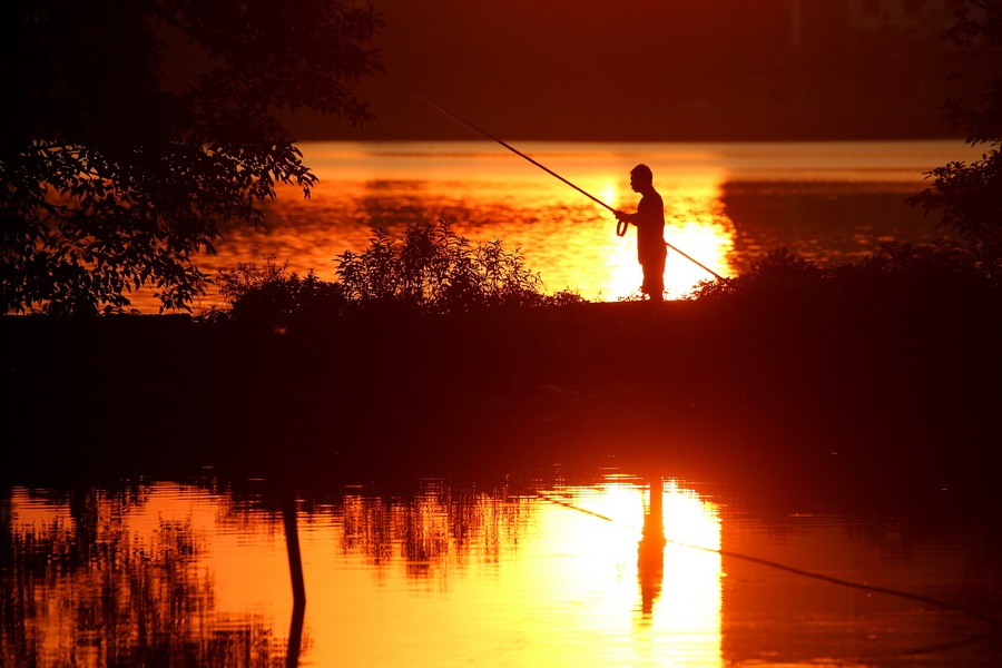 Ψυχοθεραπευτικό καρτ ποστάλ από το Ανόι: ψάρεμα με καλάμι στη χρυσοπόρφυρη λίμνη της ώρας του δειλινού καθώς τα πάντα ησυχάζουν 