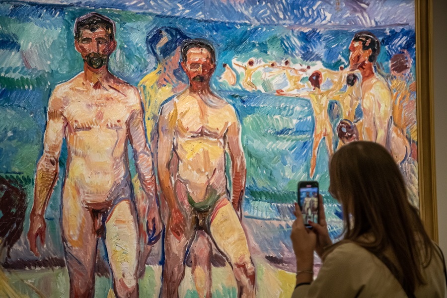 Κραυγαλέα μηνύματα αυτός ο πίνακας του Εντβαρτ Μουνκ δεν μεταδίδει, σε αντίθεση με την πασίγνωστη «Κραυγή» του, ωστόσο η γυναίκα τον φωτογραφίζει με το κινητό της επειδή τα γυμνά ανδρικά σώματά του ανήκουν σε πρόσωπα αλλοτινών καιρών: έχουν αδρά στοιχεία, εργατικά, εκτός κυκλοφορίας πια λόγω τρυφηλής ζωής και μαλθακής μόδας – καρέ από το παρισινό Μουσείο Ορσέ που ήταν κάποτε σταθμός και του λείπουν τα τρένα