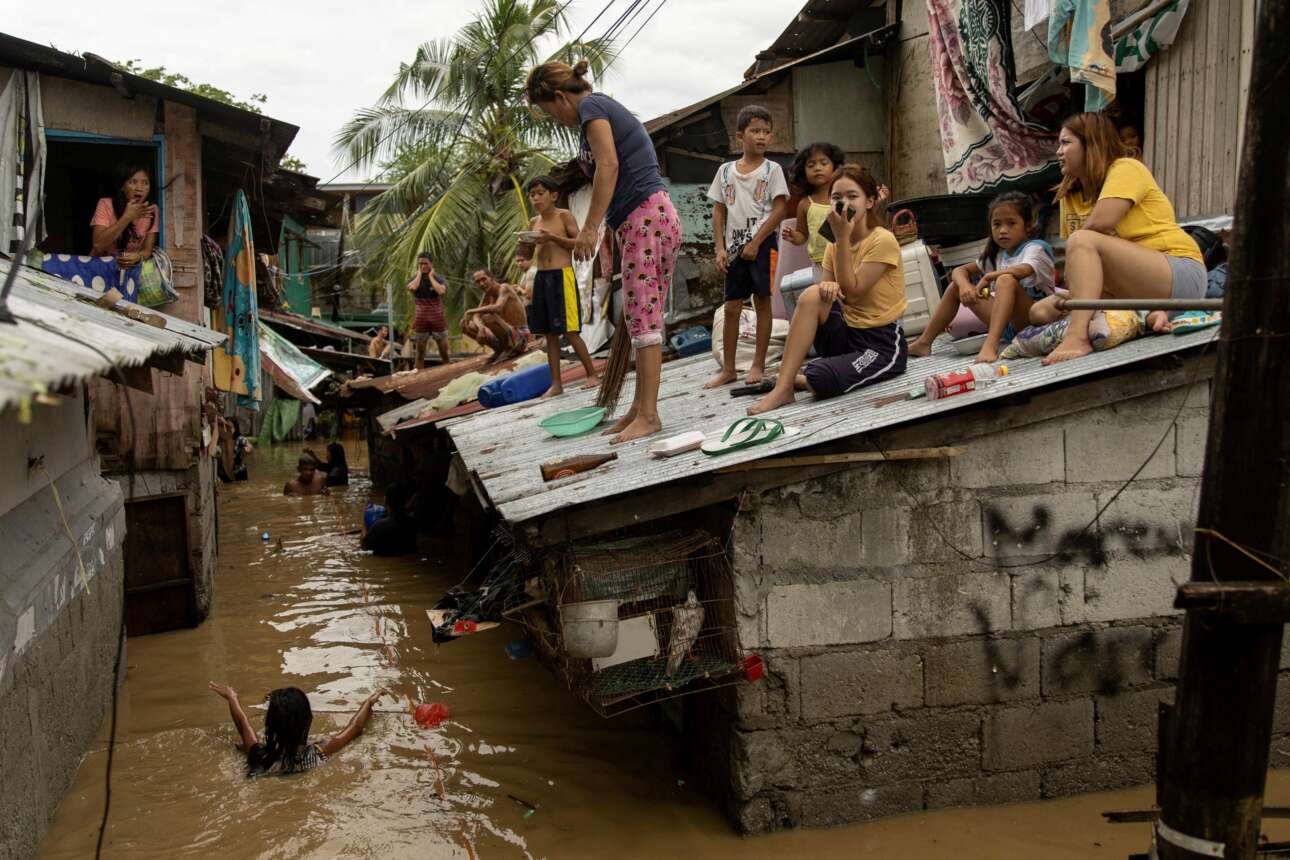 Στις τσίγκινες σκεπές των παραπηγμάτων τους σκαρφάλωσαν αυτοί οι Φιλιππινέζοι για να γλιτώσουν από την πλημμύρα: ένα κοριτσάκι έσωσε το κινητό του, ένας πιτσιρίκος το πιάτο του, κ.λπ. – όλους τους βάρεσε ο «σούπερ τυφώνας» που λέγεται Νόρου 