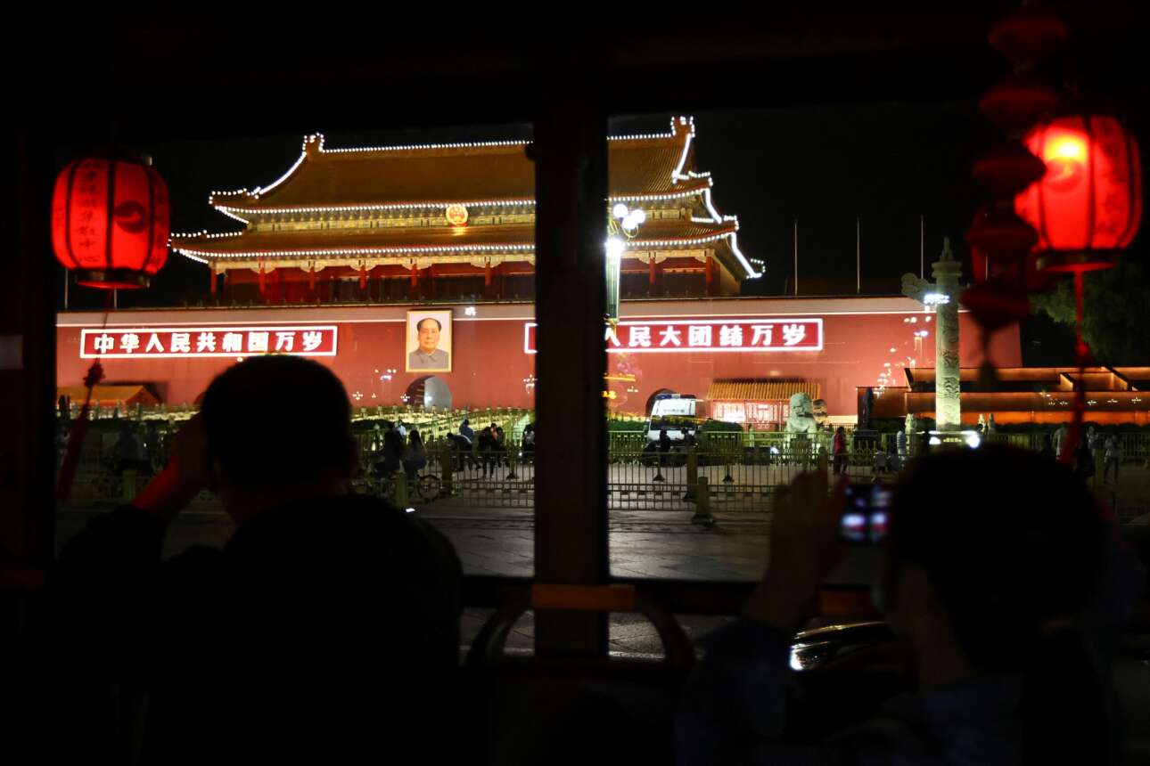 Νυχτερινή ξενάγηση με λεωφορείο στα αξιοθέατα του Πεκίνου: οι τουρίστες –κινέζοι επαρχιώτες– μόλις αντίκρισαν την πλατεία Τιενανμέν έβγαλαν τα κινητά τους τηλέφωνα και απαθανάτισαν την πύλη που κοσμείται από το πορτρέτο του προέδρου Μάο 