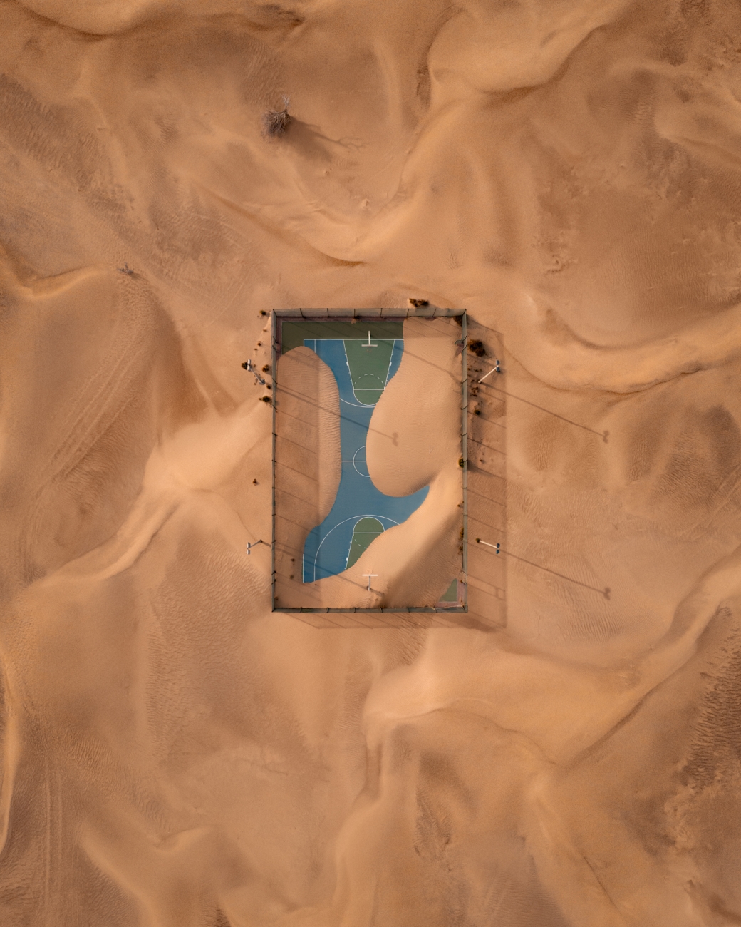 Επιλαχών στην κατηγορία Αστικό. Ενα γήπεδο μπάσκετ μετά από αμμοθύελλα στα Ηνωμένα Αραβικά Εμιράτα. Η άμμος καλύπτει κομμάτι του γηπέδου, αφήνοντας ωστόσο τον θεατή να πάρει μια ιδέα από τα αρχικά του σχήματα και χρώματα