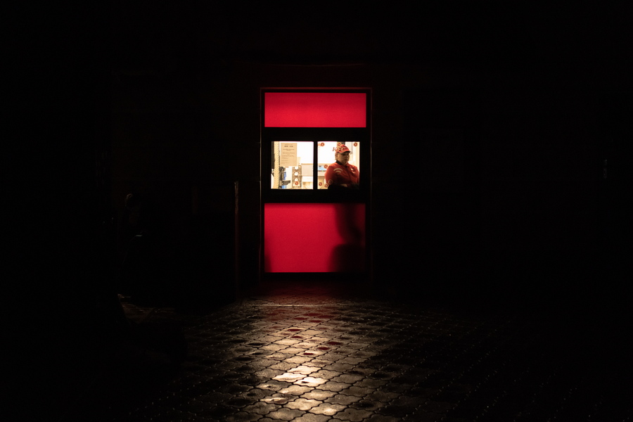 Υπάλληλος φαστφουντάδικου περιμένει πελάτες σε έναν σκοτεινό δρόμο στη γειτονιά Podil 
